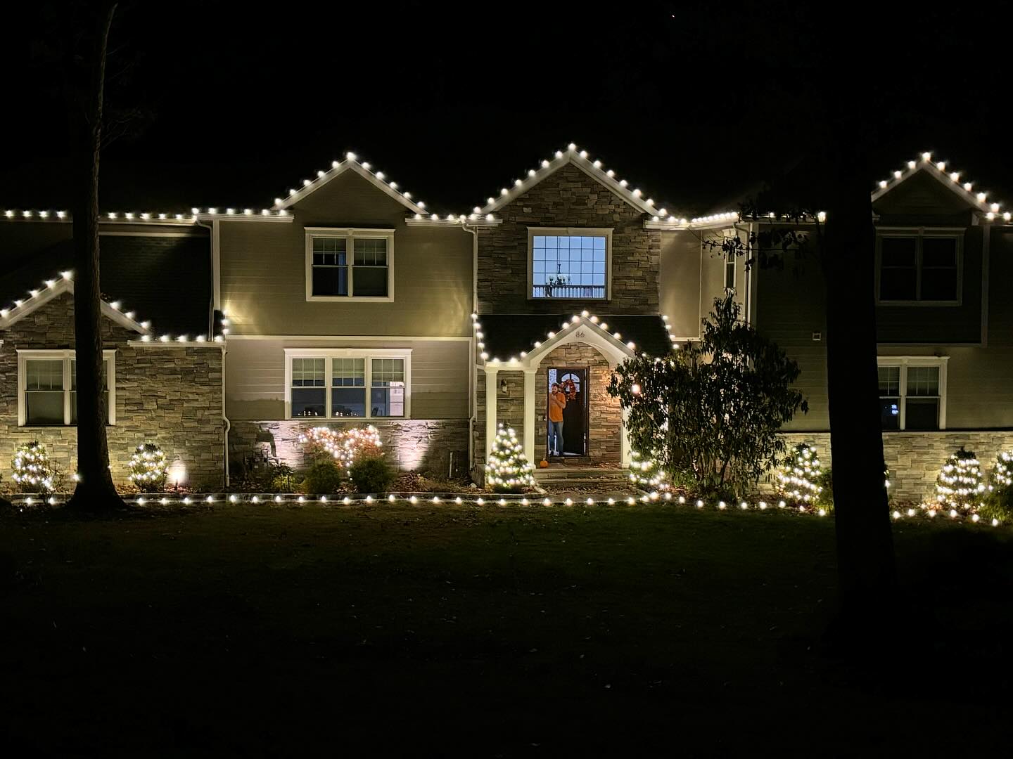 Stone siding home holiday lighting NJ tree and roofline